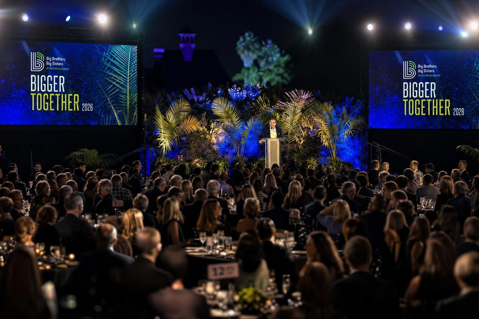 Keynote speaker on stage at a gala with flashy dual LED screens showing cinematic motion-graphics branding